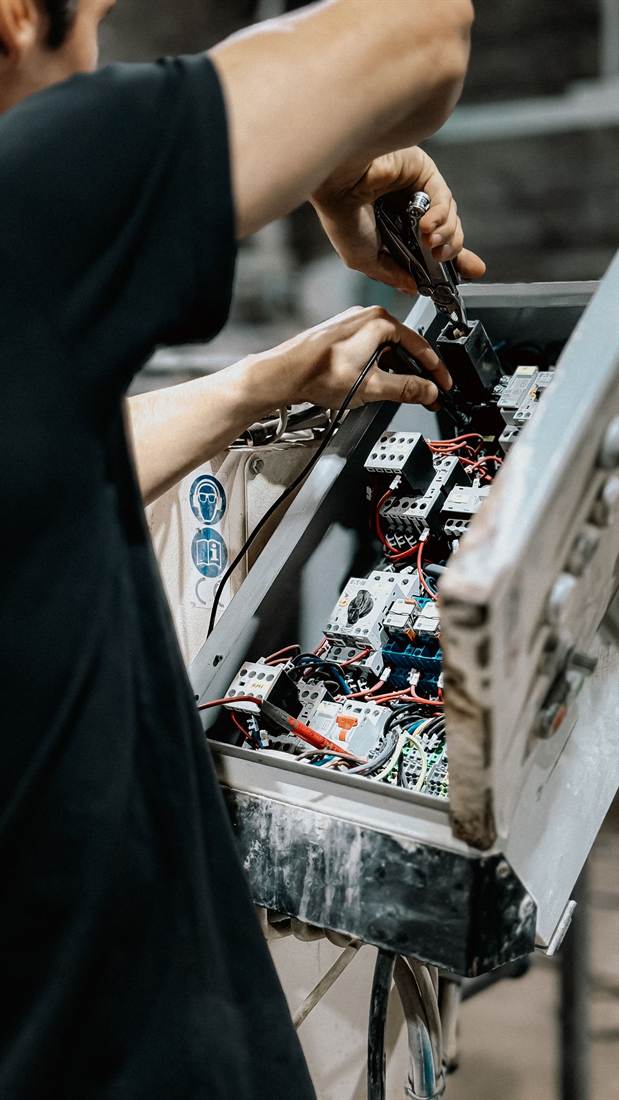 Electrician working inside an open electrical panel