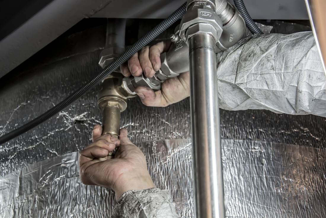 Technician tightening a brass fitting on a supply line